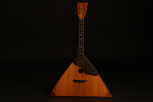 Russische Balalaika mit dreieckigem Holzkorpus und drei Saiten, freigestellt vor schwarzem Hintergrund