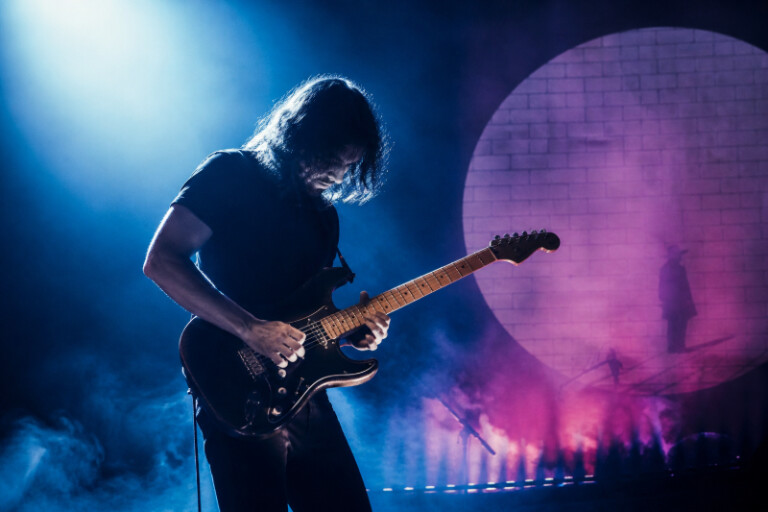 Gitarrist spielt emotionales Solo von Comfortably Numb unter blau-violettem Licht
