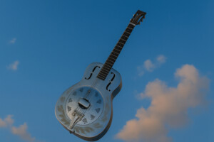 Schwebende Resonator-Gitarre vor blauem Himmel – symbolisches Artikelbild zur Analyse von „Brothers in Arms“ von Dire Straits