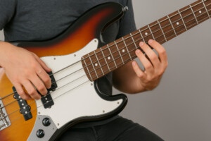 E-Bass spielen – Detailaufnahme eines elektrischen Basses mit Händen am Griffbrett