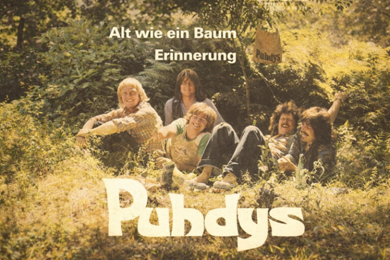Vintage Albumcover der Puhdys: Fünf Männer sitzen entspannt im Grünen unter Bäumen, sonnige Stimmung, Schriftzug 'Alt wie ein Baum Erinnerung' im Vordergrund
